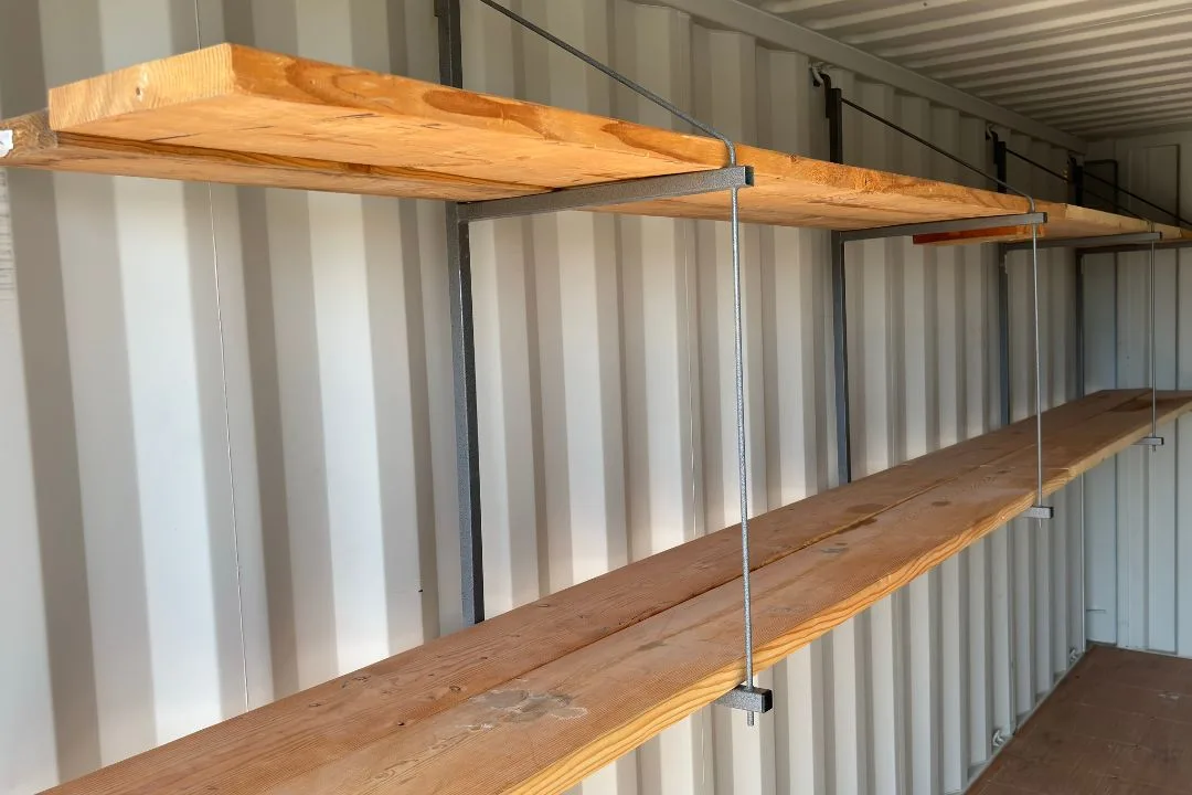 Close-up of steel bracket arms and heavy lumber planks showing the shelving mounting system on a
